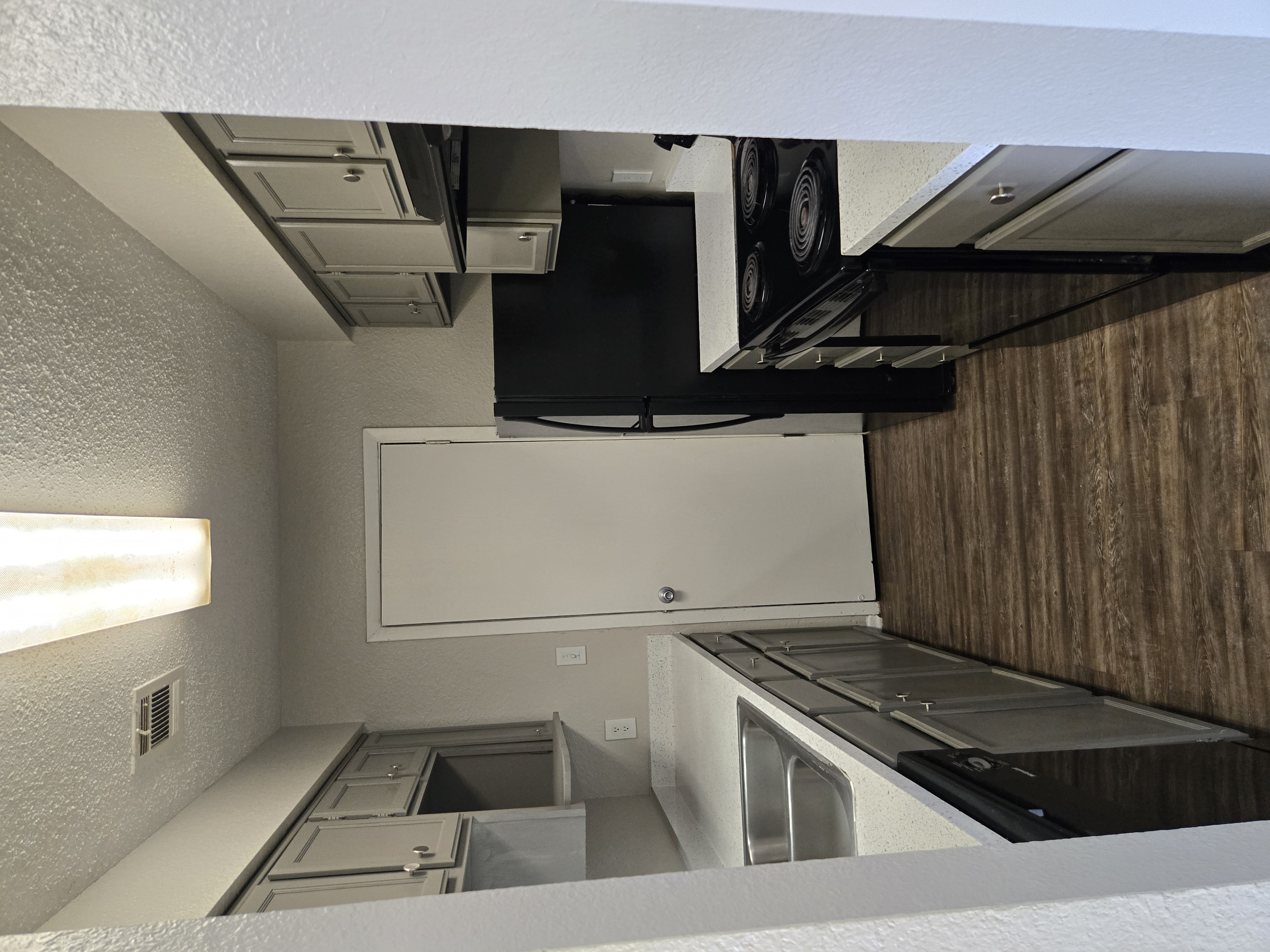 A kitchen with a white counter and a black fridge.